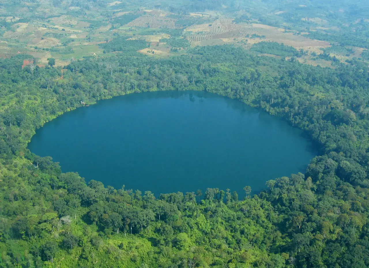 Aerial view of an almost perfectly round blue lake ringed by forest